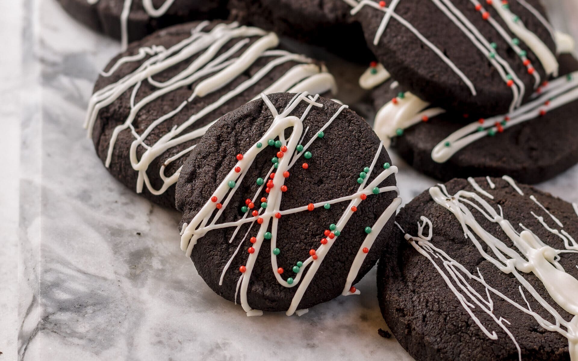 chocolate short bread cookies on a platter decorated with white chocolate drizzle and sprinkles